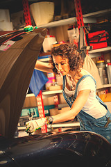 Image showing woman mechanic with a wrench adjusts the car\'s engine