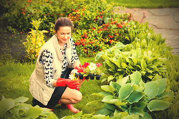 Image showing smiling middle-aged woman in red rubber gloves planting flowers