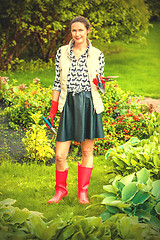 Image showing smiling middle-aged woman in red rubber boots planting flowers