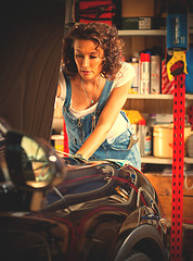 Image showing car mechanic in jeans overalls adjusts car engine