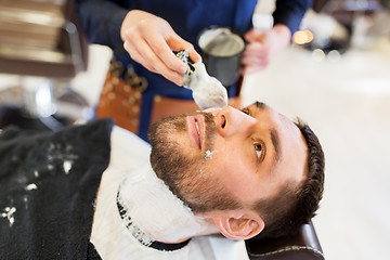 Image showing man and barber applying shaving foam to beard