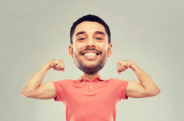 Image showing smiling man showing biceps over gray background