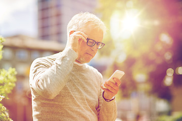 Image showing senior man texting message on smartphone in city