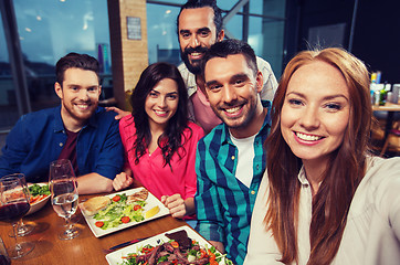 Image showing friends taking selfie by smartphone at restaurant