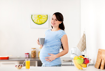 Image showing happy pregnant woman with cup at home kitchen