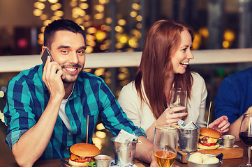 Image showing man with smartphone and friends at restaurant