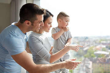 Image showing happy family looking through window at home