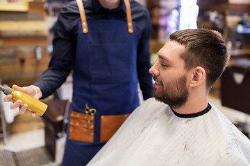 Image showing barber showing hair styling spray to male customer