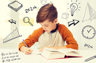 Image showing student boy with book writing to notebook at home