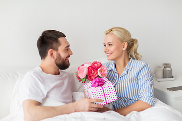 Image showing happy couple with gift box in bed at home