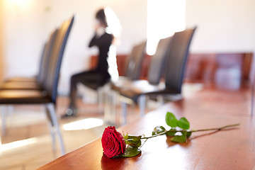 Image showing red roses and woman crying at funeral in church