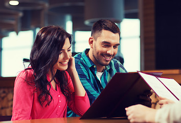 Image showing smiling couple with menus at restaurant