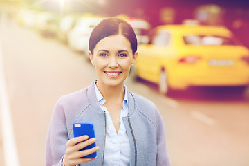 Image showing smiling woman with smartphone over taxi in city