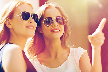 Image showing happy women in sunglasses pointing finger outdoors