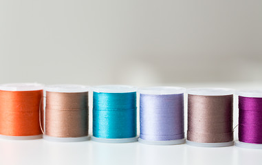 Image showing row of colorful thread spools on table