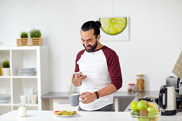 Image showing man with smartphone having breakfast at home