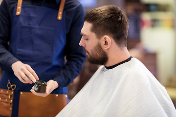 Image showing barber showing hair styling wax to male customer