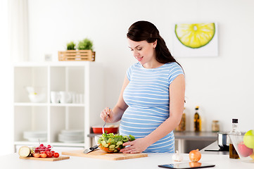 Image showing pregnant woman cooking vegetable salad at home