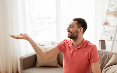 Image showing happy man holding something imaginary at home