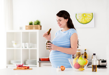 Image showing pregnant woman eating pickles at home kitchen