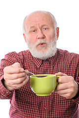 Image showing Cheerfull senior man with green cup and teaspoon, isolated on white