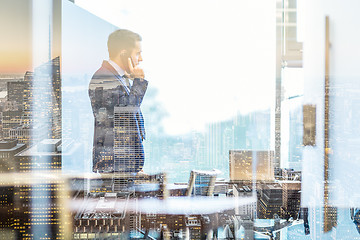 Image showing Businessman talking on a mobile phone while looking through window in NY