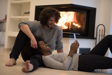 Image showing multiethnic couple using tablet computer on the floor