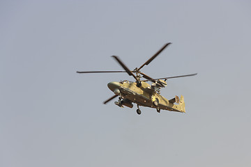 Image showing Green helicopter flies against the blue sky