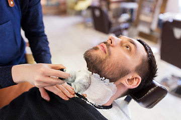 Image showing man and barber applying shaving foam to beard