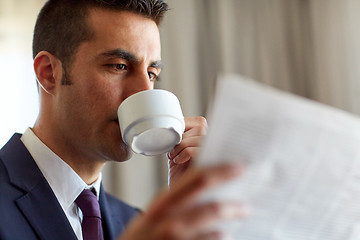 Image showing businessman reading newspaper and drinking coffee