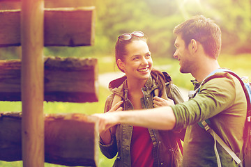 Image showing smiling couple at signpost with backpacks hiking