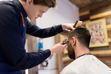 Image showing man and barber with trimmer cutting hair at salon