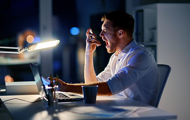 Image showing angry businessman with smartphone at night office