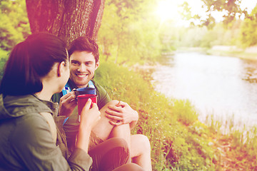 Image showing happy couple with cups drinking in nature