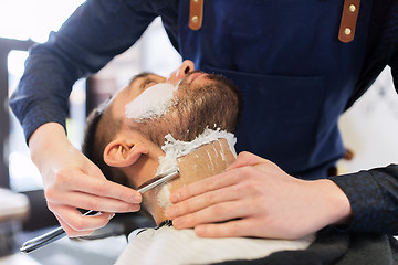 Image showing man and barber with straight razor shaving beard