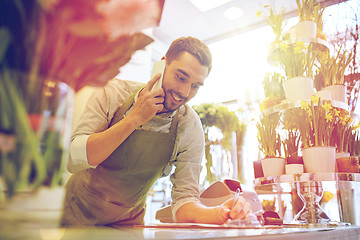 Image showing man with smartphone making notes at flower shop