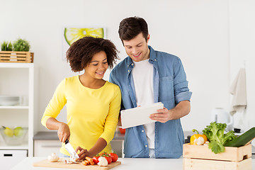 Image showing happy couple with tablet pc cooking food at home