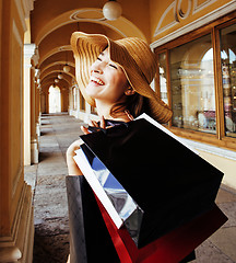 Image showing young pretty smiling woman in hat with bags on shopping at store