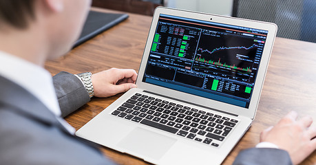 Image showing Young businessman analyzing economic data on laptop computer.