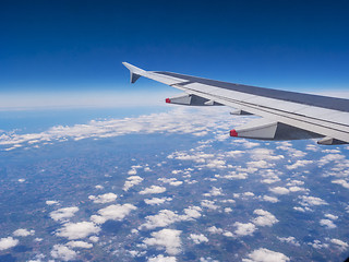 Image showing View from a plane window: a plane wing over clouds and blue sky