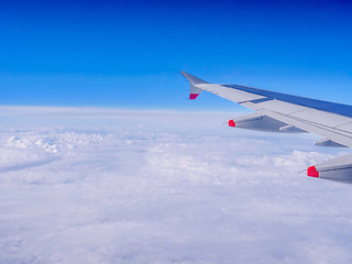 Image showing View from a plane window: a plane wing over clouds and blue sky