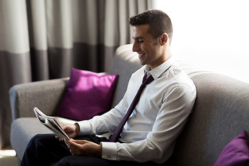 Image showing happy businessman reading newspaper at hotel room