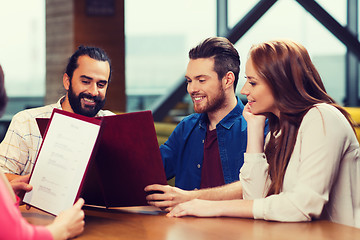 Image showing smiling friends discussing menu at restaurant