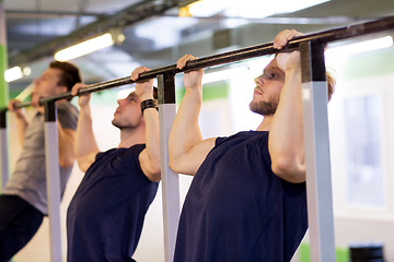 Image showing group of young men doing pull-ups in gym