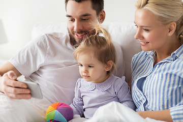 Image showing happy family with smartphone in bed at home