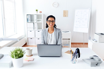 Image showing happy businesswoman with laptop working at office