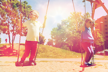 Image showing two happy kids swinging on swing at playground