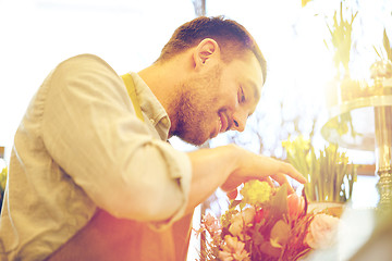 Image showing smiling florist man making bunch at flower shop