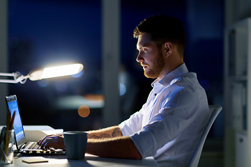 Image showing man with laptop and coffee working at night office