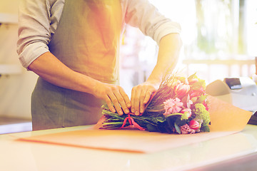 Image showing florist wrapping flowers in paper at flower shop